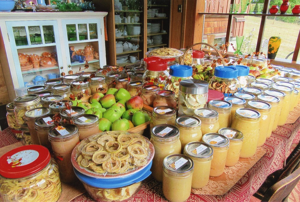 Un assortiment de conserves et de fruits présentés sur une table de ferme.