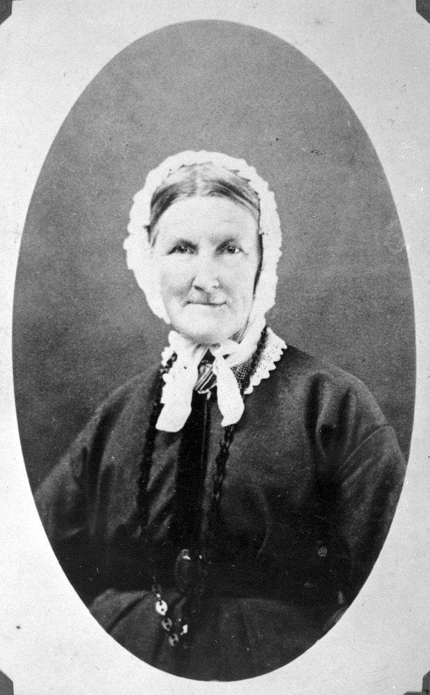 Portrait photo en noir et blanc d’une femme portant un bonnet blanc.