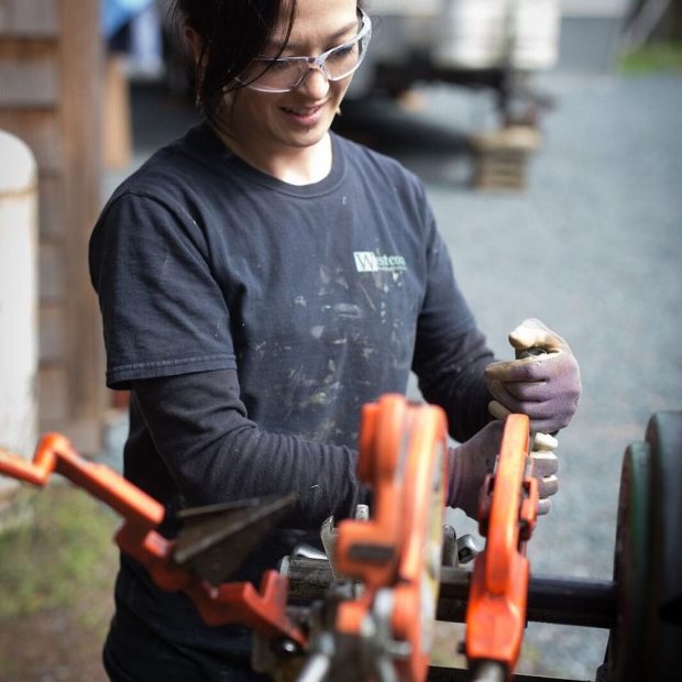 Une femme utilisant une machine à fileter les tuyaux.