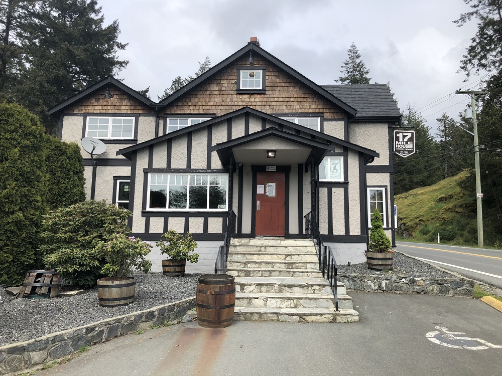 Une grande maison à plusieurs niveaux, sur une rue en pente, des marches menant à la porte d’entrée rouge.