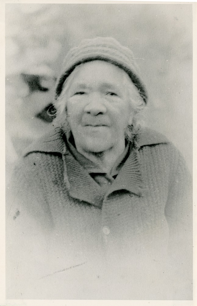 Portrait photo en noir et blanc d’une femme âgée portant un bonnet et un chandail tricotés.
