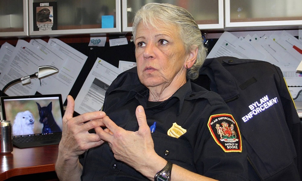 Dans un bureau, une femme en uniforme policier parlant de manière animée, les mains devant elle.