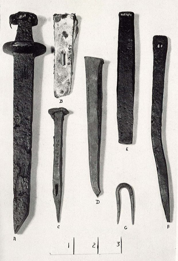 Sept objets en fer rouillé, dont une dague, trouvés au cours des fouilles, classés selon leur forme et leur taille.