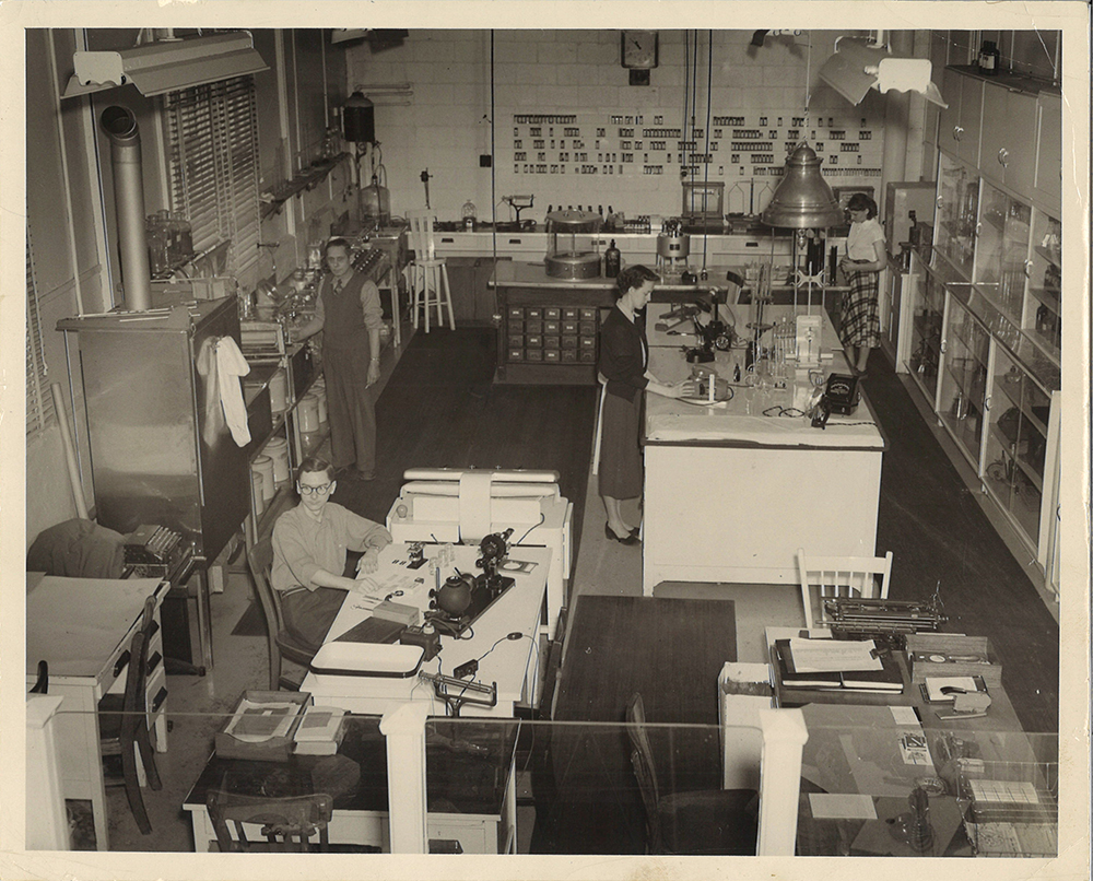 Photo noir et blanc du laboratoire de la Bruck Mills avec deux employés au travail.