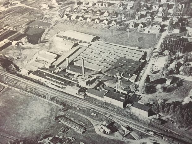 Photo aérienne de l’usine de la Bruck Mills avec le chemin de fer adjacent et des maisons de travailleurs.