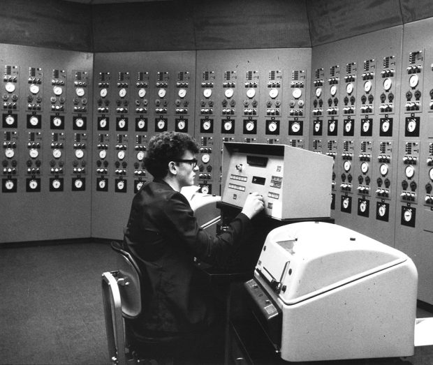 Un employé est assis devant son poste de travail dans une salle de contrôle d’ordinateurs