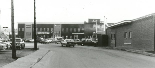 L’entrée de l’usine Bruck Silk Mills avec des automobiles datant des années 1970 stationnées devant.