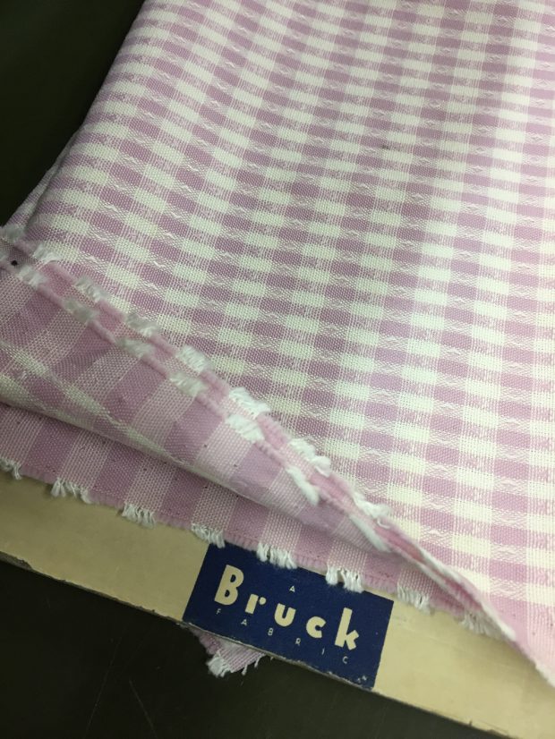 Échantillon de tissus enroulé autour d’un support en carton identifié avec le logo Bruck Fabrics.