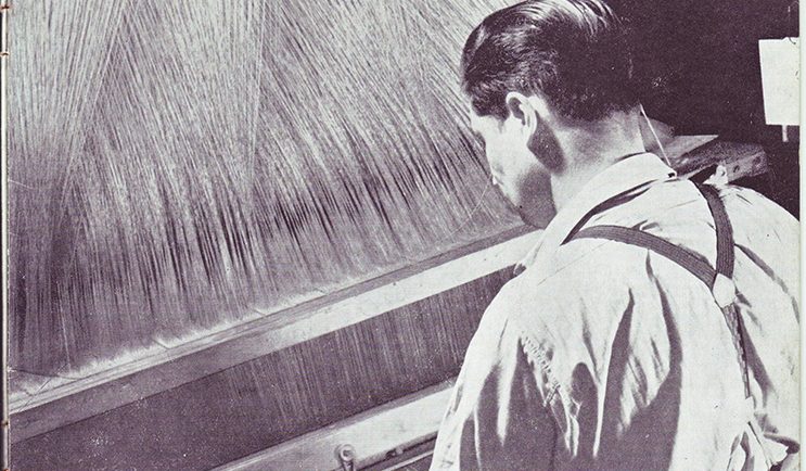 Photo noir et blanc d'un homme vu de dos devant un métier à tisser