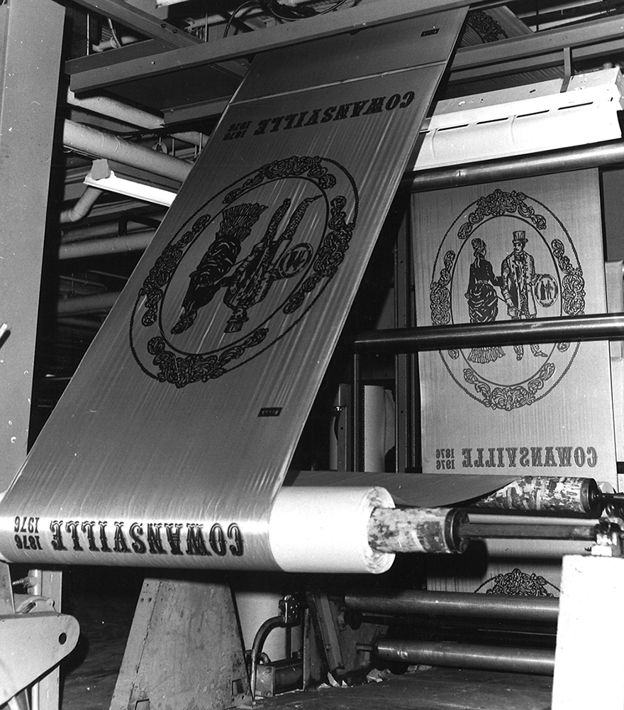 Deux gros rouleaux de tissus montés sur une machine avec une illustration ancienne et les mots Cowansville 1976