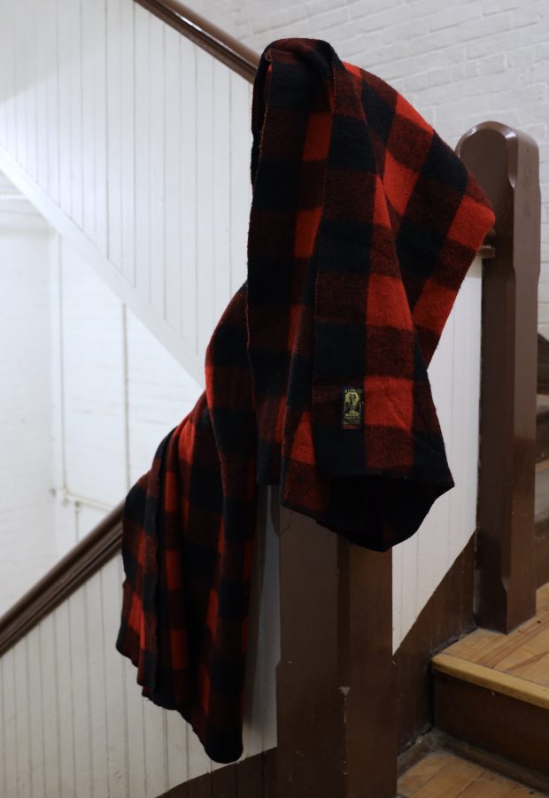 Couverture à carreaux rouge et noire drapée sur une cage d'escalier.