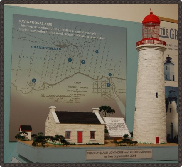 Maquette d’une petite maison et d’un grand phare èa son côté. Derrière, on voit une carte montrant les différents endroits où ils se trouvaient.