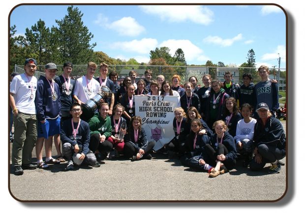 Photo du groupe d’élèves de l’école Netherwood de Rothesay qui a gagné le trophée Équipage de Paris à l’été 2017. Des élèves tiennent une bannière qui indique 2017 Paris Crew High School Rowling Champions école secondaire championne de la compétition d’aviron Équipage de Paris 2017. Tous les membres de l’équipe présents sur la photo portent une médaille à lanière rose autour du cou.