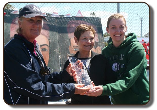 Image du trophée Équipage de Paris remis aux deux entraineurs de l’école Netherwood de Rothesay (Nouveau-Brunswick) à l’été 2017. À côté d’eux se trouve la mairesse de Rothesay. Le trophée en question est un vase en cristal clair portant des gravures décoratives texturées. Le haut du trophée est coupé en angle et le dos du trophée est plus haut que le devant. Gravé au dos de la pièce, au centre, rendu plus clair par la façon dont elle a été coupée, on peut y lire le nom du trophée.