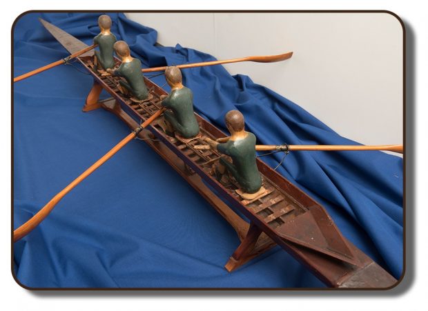 Image d’une réplique en bois du célèbre aviron J. A. Harding qui aurait été utilisé par l’équipage de Paris à la Régate internationale d’aviron, à Paris, en France. Ce modèle mesure environ 3 pieds de long et comprend quatre figurines représentant les quatre membres de l’équipage.