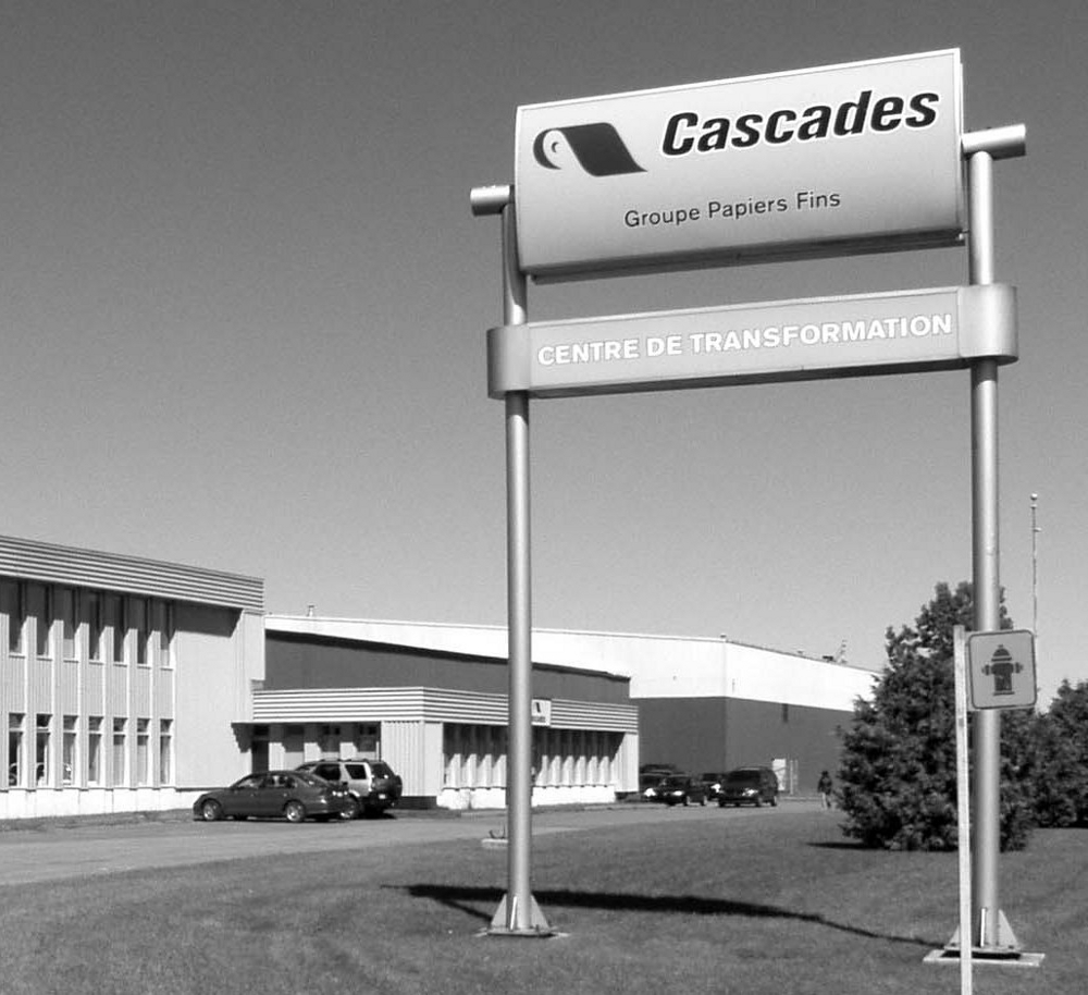 Photographie noir et blanc de l’affiche du centre de transformation de Cascades devant la bâtisse. 