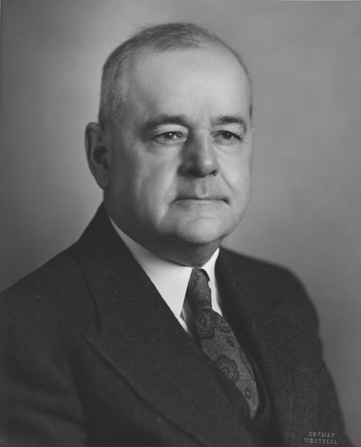 Photographie noir et blanc d’un homme en complet avec une cravate. 