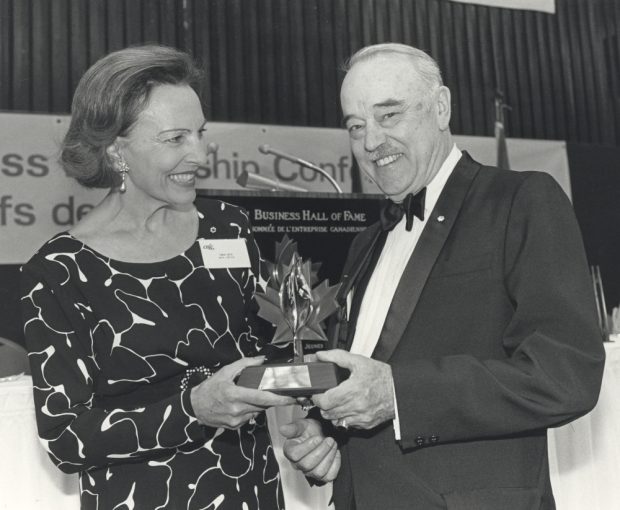Photographie noir et blanc d’une femme et d’un homme tenant un trophée dans leurs mains. 
