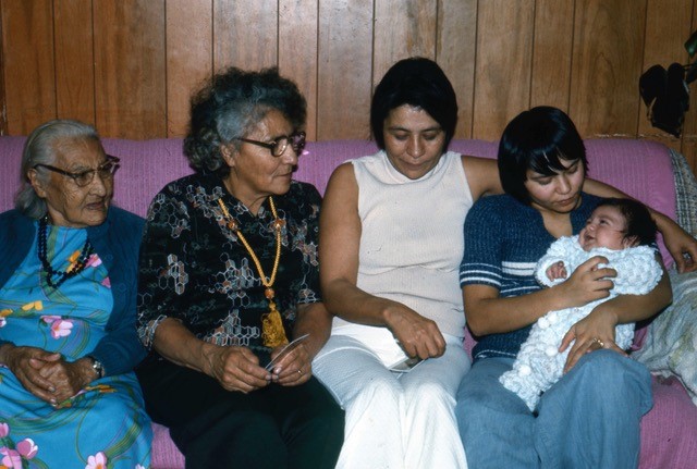  Photo couleur d'un groupe de femmes assises sur le canapé rose à l'extrême gauche: Granny Powder, Katy Sanderson et leurs enfants avec cinq générations de femmes.