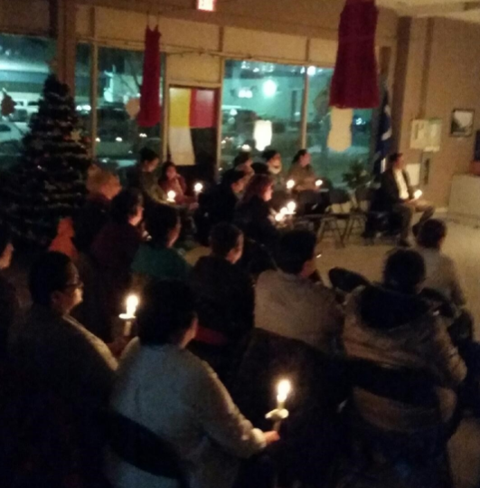 Une photo en couleur d'un groupe de personnes assises qui tiennent les bougies.