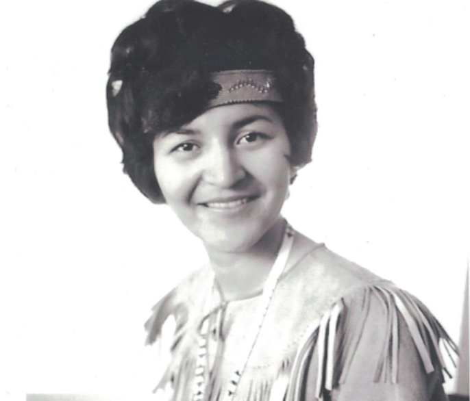 Portrait en noir et blanc d'une jeune Dorothy McDonald avec un bandeau autour du haut de son front, les cheveux noirs courts tombant, portant une robe traditionnelle et regardant droit devant elle.