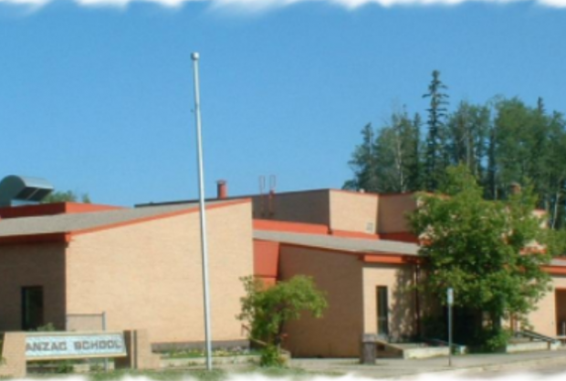 Une vue de l'Anzac School dans les années 90, par une journée ensoleillée, avec les arbres d'un vert vif et le toit en tôle de l'école d'une couleur orange intense.