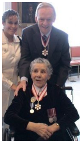 Bertha Clark Jones est assise sur un fauteuil roulant avec l'ancien Premier ministre Jean Chrétien debout derrière elle.