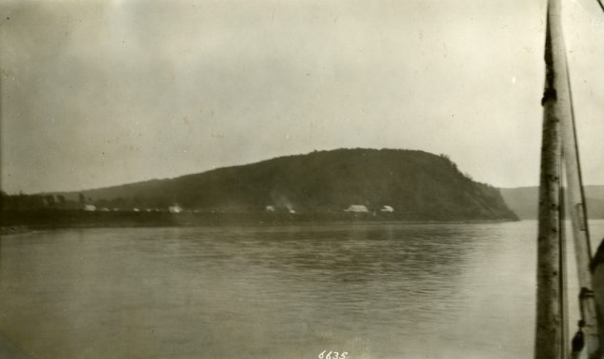 Photo en noir et blanc d'un terrain vallonné traversant une étendue d'eau.