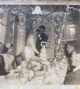 la mariée et le marié sont représentés en train de couper le gâteau de mariage au dîner de mariage d'Alice Drake à Oderin. les invités et les membres de la noce regardent