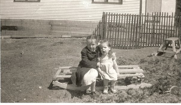 Deux fillettes assises sur un traîneau en bois