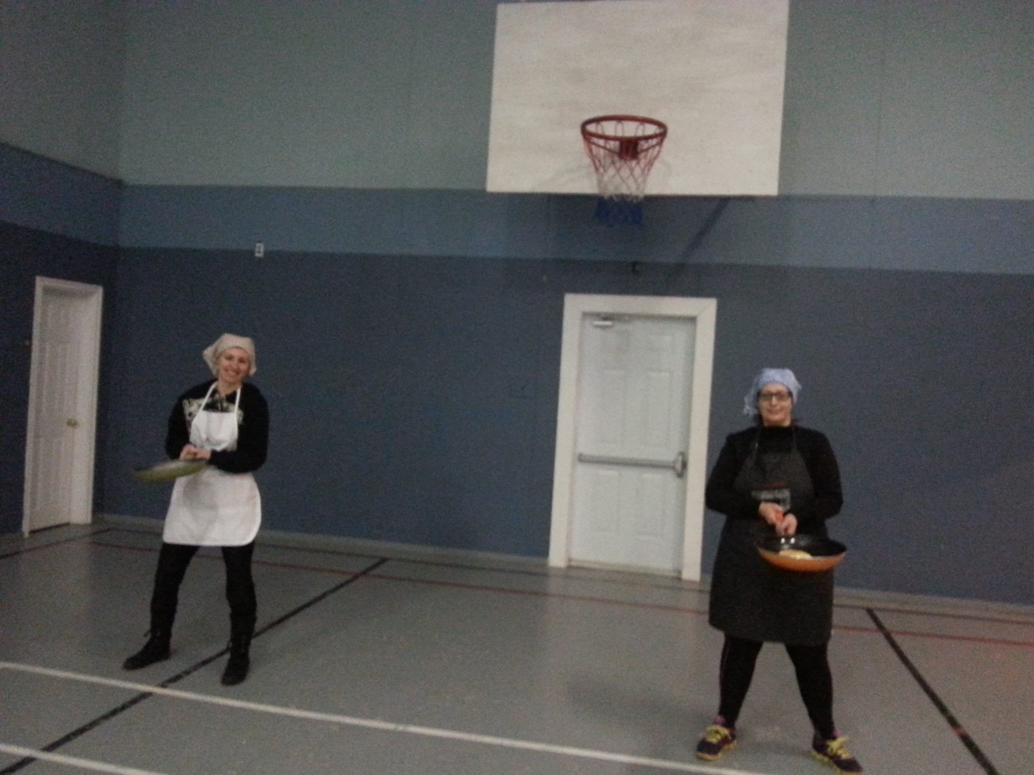 Deux femmes debout avec des poêles à frire et des pancakes prêtes pour la course aux crêpes