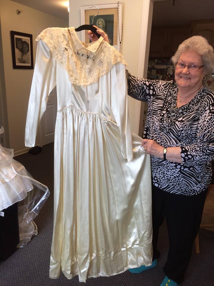 Une femme âgée montre fièrement sa robe de mariée en satin blanc