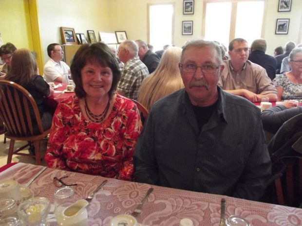 Une femme et un homme assis à une table lors d’un repas de fête communautaire.