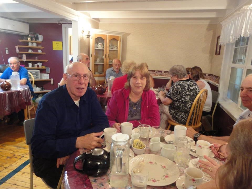 Frank et Ann Murphy assis ensemble à une table lors d’une soirée des anciens. D’autres personnes âgées apparaissent en arrière-plan.