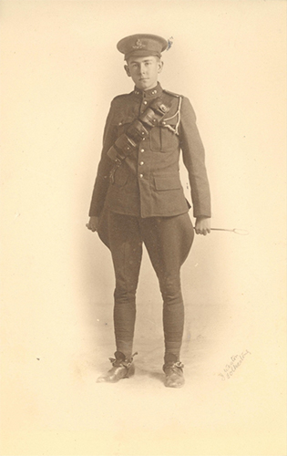 Photo d’un soldat debout, tenant un fouet derrière le dos avec les deux mains.