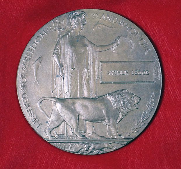 Une plaque de cuivre circulaire représentant l’image d’une femme tenant des feuilles de laurier et un lion devant elle.