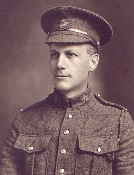 Portrait d’un soldat portant une casquette. Il a une moustache. On peut remarquer des poches poitrine, des boutons et des insignes de collet.