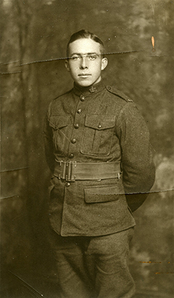 Un soldat tenant ses bras derrière le dos; il porte un ceinturon à la taille; on peut remarquer des poches poitrine et des poches plus bas.