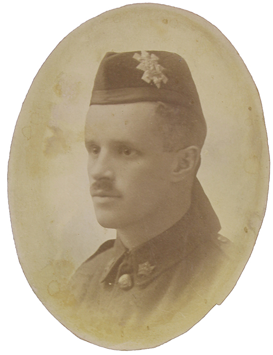 Portrait d’un soldat à la moustache. Il porte un calot pourvu d’un insigne et de rubans sur le derrière (Highlander).