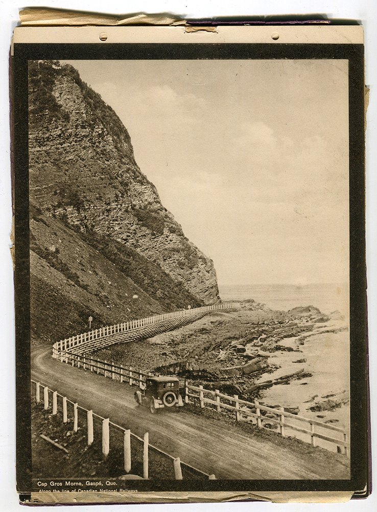 Cette photographie du boulevard Perron vers 1930, nous montre la splendeur des paysages qu’offrait le boulevard, mais aussi ses difficultés. La route de gravier qu’était le boulevard Perron passe au pied d’un cap rocheux à Saint-Antoine-du-Gros-Morne en longeant la rive du fleuve Saint-Laurent.