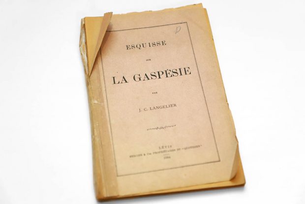 Photographie couleur du livret. Sur la page couverture, on peut y lire : Esquisse sur la Gaspésie par J. C. Langelier, Lévis, Mercier & Cie, Propriétaires du quotidien, 1886. La couverture est faite d’un papier cartonné fin jauni par l’acidité du carton. 