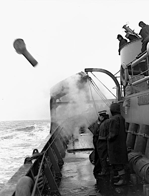 Des marins sur un navire de guerre lançant une grenade sous-marine. 