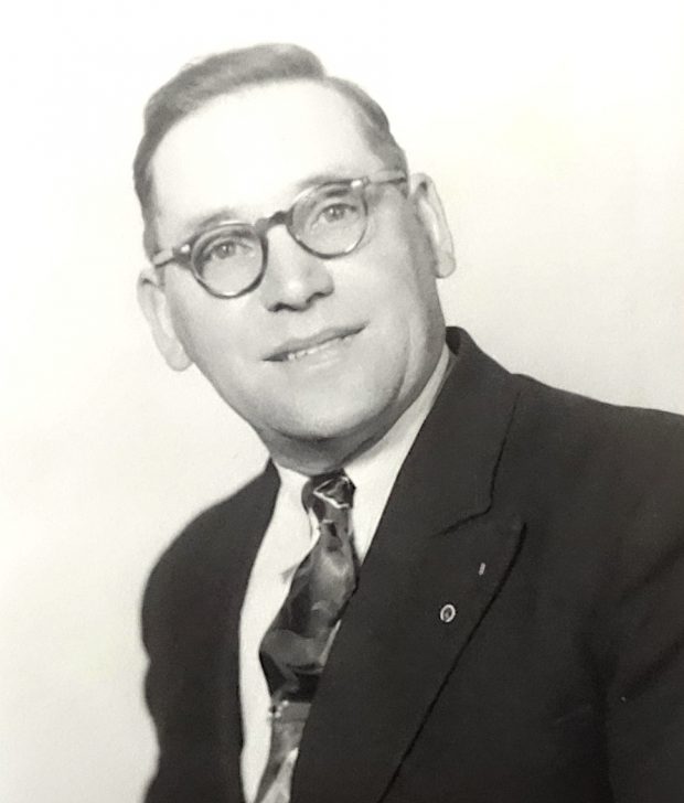 Un homme portant des lunettes et vêtu d’un costume et d’une cravate.