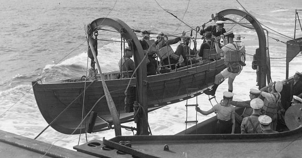 Marins montant dans un canot de sauvetage sur le flanc d’un navire