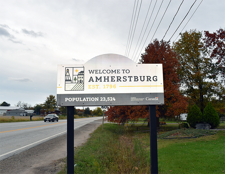 Panneau de bienvenue pour Amherstburg, Ontario, établie en 1796, population 23 524, avec des arbres montrant un feuillage automnal en arrière-plan.