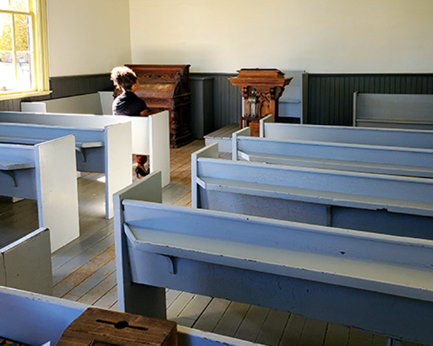Gabriela assise sur un banc de bois à l'intérieur de l'église historique du Musée Josiah Henson à Dresden.