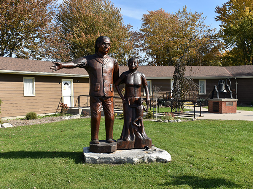 Sculpture en bois d'une famille cherchant la liberté, sculptée par Grant Bone, située au Musée Josiah Henson de l'histoire des Afro-Canadiens à Dresden, en Ontario.