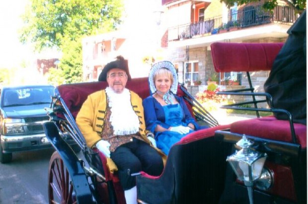 Ernest Labelle portant un tricorne et Marthe Beausoleil portant un bonnet sont assis dans une carriole.