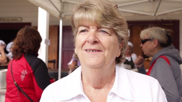 Plan poitrine de Francine Racette aux cheveux blonds courts portant une blouse blanche et se tenant à l’extérieur sous une tente.