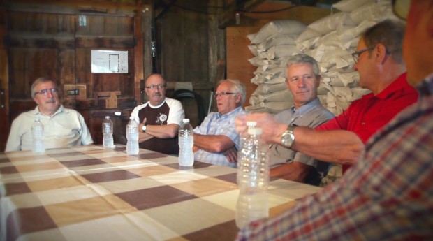 Six bénévoles sont assis autour d’une table rectangulaire et discutent entre eux.